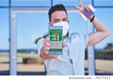 Hand man holding smartphone displaying an app mobile valid digital green vaccination certificate for Covid-19. Immunity vaccine passport, vaccination certificate, health passport for new normal travel Hand man holding smartphone displaying an app mobile valid digital green vaccination certificate for Covid-19. Immunity vaccine passport, vaccination certificate, health passport for new normal travel 79373417