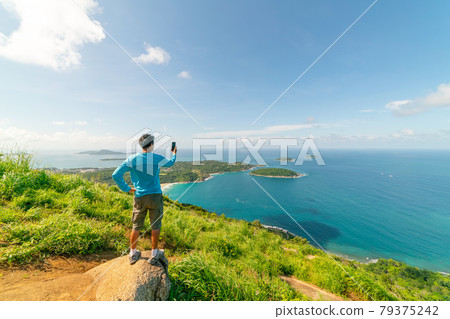 Travel man standing on rock Take a photo or video landscape view at Phahindum viewpoint popular landmark in Phuket Thailand Viewpoint to see promthep cape Naiharn beach and yanui beach Amazing view Travel man standing on rock Take a photo or video landscape view at Phahindum viewpoint popular landmark in Phuket Thailand Viewpoint to see promthep cape Naiharn beach and yanui beach Amazing view 79375242