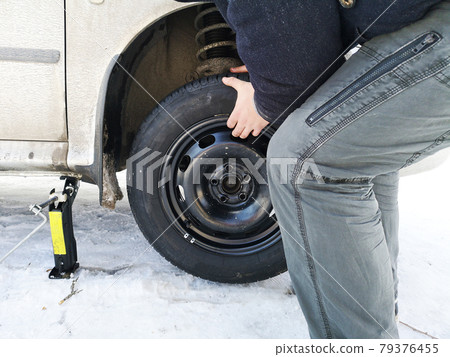 Punched and flat tire on the road. Replacing the wheel with a jack by the driver 79376455