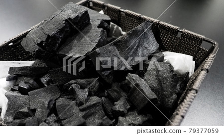 Black Charcoal on black textured floor. charcoal black carbon reesidue produced by strongly heating wood. Used for cooking or other industries. Natural wood charcoal. traditional hard wood charcoal. 79377059