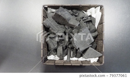 Black Charcoal on black textured floor. charcoal black carbon reesidue produced by strongly heating wood. Used for cooking or other industries. Natural wood charcoal. traditional hard wood charcoal. 79377061