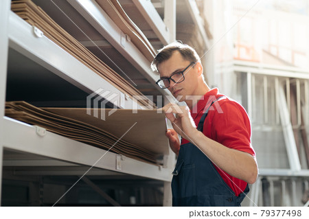 salesman of a flooring store with a sample of a laminate floor panel. 79377498