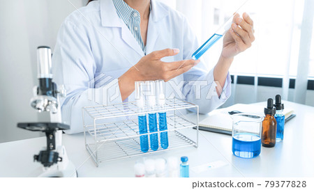 Scientist woman shaking blue liquid in test tube while working to experiment produce vaccine covid-19 79377828