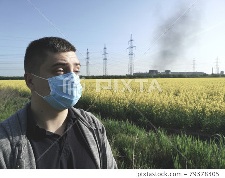 A man in a medical mask against the background of the plant. The concept of environmental pollution, ecology A man in a medical mask against the background of the plant. The concept of environmental pollution, ecology 79378305