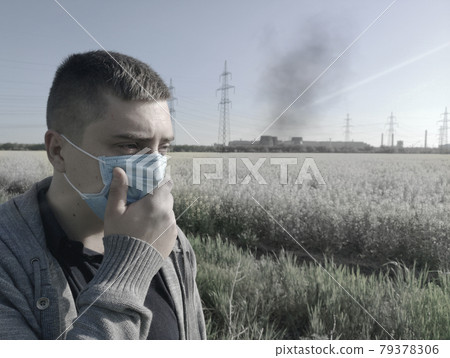 A man in a medical mask against the background of the plant. The concept of environmental pollution, ecology 79378306