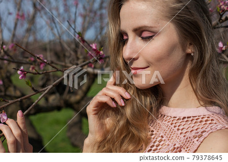 Beautiful blonde woman in pink dress in blossoming spring green garden 79378645