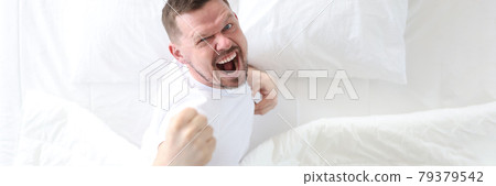 Young man lying in bed and rejoicing top view 79379542