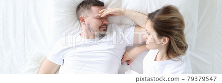 Married couple is lying in bed top view. Man holding his head 79379547