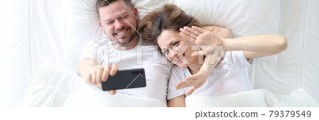 Man and woman lying in bed and taking selfie top view Man and woman lying in bed and taking selfie top view 79379549
