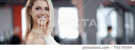 Young smiling woman lifting dumbbells in gym 79379564