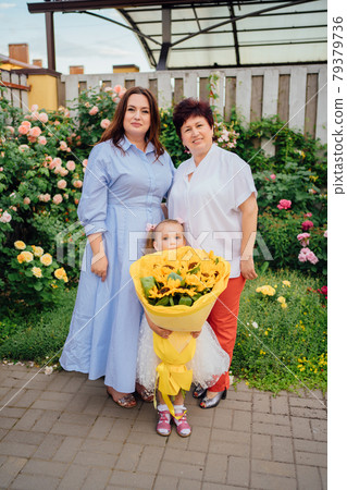 Mom, grandmother and daughter with a large bouquet of decorative sunflowers Mom, grandmother and daughter with a large bouquet of decorative sunflowers 79379736