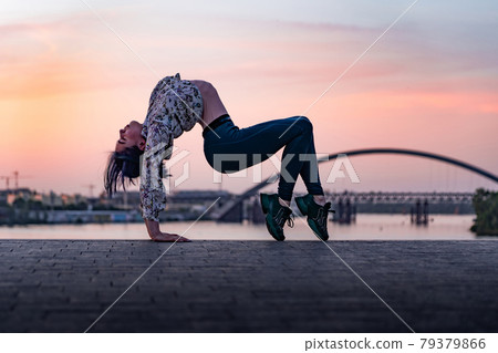 Silhouette of flexible yoga woman bending her back on dramatic sunset and cityscape. Concept of healthy lifestyle and healthcare Silhouette of flexible yoga woman bending her back on dramatic sunset and cityscape. Concept of healthy lifestyle and healthcare 79379866