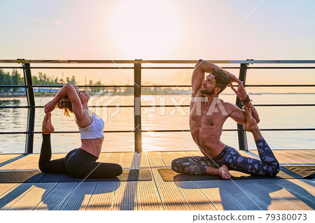 Couple doing practicing yoga together on nature outdoors . Morning exercises at the sunrise. Couple doing practicing yoga together on nature outdoors . Morning exercises at the sunrise. 79380073