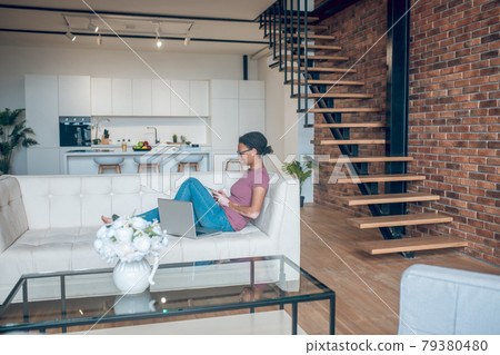 A woman in casual clothes surfing internet while resting at home 79380480