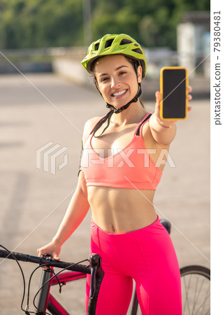 A girl in pink portswear showing her smartphone and looking excited A girl in pink portswear showing her smartphone and looking excited 79380481