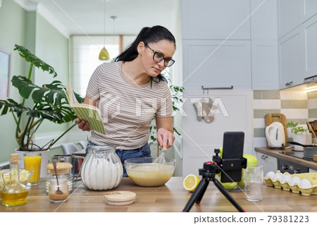 Woman preparing apple pie at home in kitchen, talking online using video call 79381223