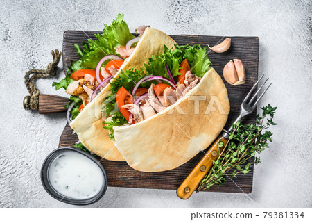 Pita sandwich with roasted chicken, vegetables and delicious sauce. White background. Top view Pita sandwich with roasted chicken, vegetables and delicious sauce. White background. Top view 79381334