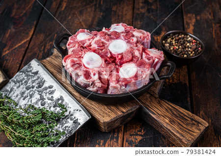 Raw veal beef Oxtail Meat on butcher wooden board with cleaver. Dark wooden background. Top view Raw veal beef Oxtail Meat on butcher wooden board with cleaver. Dark wooden background. Top view 79381424