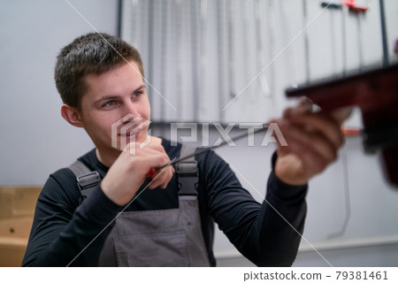 Portrait of concentrated young dent removing specialist on car repair station 79381461
