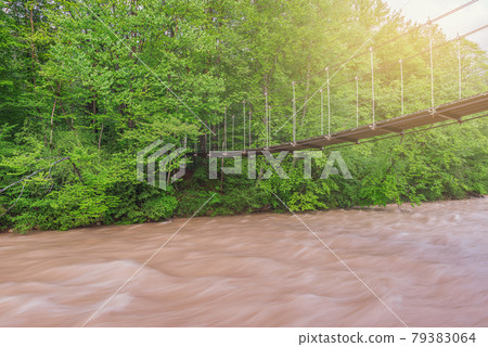 Suspension bridge above the river at sunset. 79383064