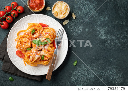 Tasty appetizing classic italian tagliatelle pasta with tomato sauce, cheese parmesan and basil on plate on dark table. View from above, horizontal. Top view with copy space Tasty appetizing classic italian tagliatelle pasta with tomato sauce, cheese parmesan and basil on plate on dark table. View from above, horizontal. Top view with copy space 79384479
