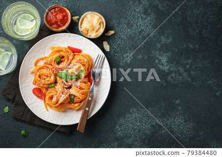 Tasty appetizing classic italian tagliatelle pasta with tomato sauce, cheese parmesan and basil on plate on dark table. View from above, horizontal. Top view with copy space 79384480