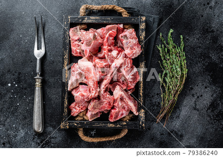 Raw diced meat with bone in a wooden tray. Black background. Top View Raw diced meat with bone in a wooden tray. Black background. Top View 79386240