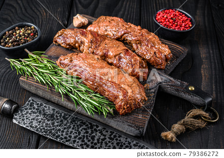 Marinated brisket steaks in bbq sauce on a wooden cutting board with herbs. Black wooden background. Top view Marinated brisket steaks in bbq sauce on a wooden cutting board with herbs. Black wooden background. Top view 79386272