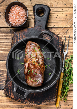 Grilled veal fillet meat steak in a pan with herbs. wooden background. Top view 79386363
