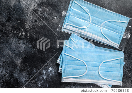Doctor mask and corona virus protection. Disposable procedural face mask with malleable nose clip. Black background. Top view. Copy space Doctor mask and corona virus protection. Disposable procedural face mask with malleable nose clip. Black background. Top view. Copy space 79386528