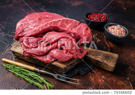 Raw Beef meat fillet Sliced on wooden cutting board. Dark background. Top view Raw Beef meat fillet Sliced on wooden cutting board. Dark background. Top view 79386608