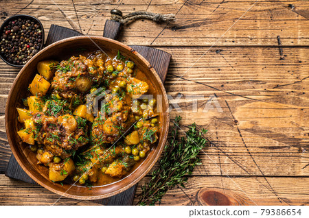 Lamb oxtails tails stew with vegetables in a wooden plate. wooden background. Top view. Copy space Lamb oxtails tails stew with vegetables in a wooden plate. wooden background. Top view. Copy space 79386654