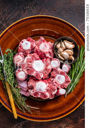 Fresh uncooked beef Oxtail cut Meat on rustic plate with herbs. Dark background. Top view 79386659