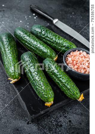 Ripe Green Cucumbers on a marble board. Black background. Top view Ripe Green Cucumbers on a marble board. Black background. Top view 79386788