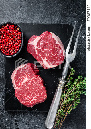 Prime Raw Fillet Mignon tenderloin steaks with thyme. Black background. Top view Prime Raw Fillet Mignon tenderloin steaks with thyme. Black background. Top view 79387111