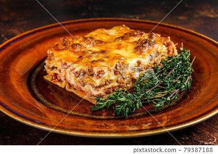 Italian Lasagne with tomato bolognese sauce and mince beef meat on a rustic plate. Dark background. Top view Italian Lasagne with tomato bolognese sauce and mince beef meat on a rustic plate. Dark background. Top view 79387188