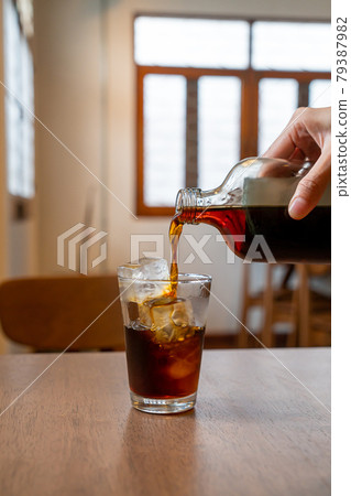 pouring cold brew coffee in glass with ice cube 79387982