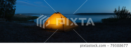 Orange illuminated tourist tent on lake in evening Orange illuminated tourist tent on lake in evening 79388677