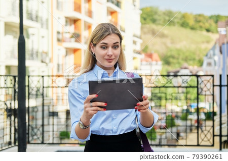 Surprised young business woman looking emotionally into digital tablet screen 79390261
