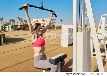 Mature woman doing sports exercises on outdoor simulators 79390495