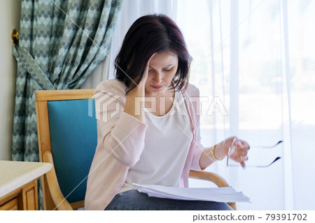 Sad emotion on face of mature woman reading paper letter, contract, document. 79391702