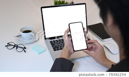 Close up over shoulder view of businessman using smart phone. 79392254