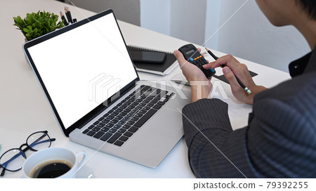 Businessman using calculator and working with laptop at office. 79392255