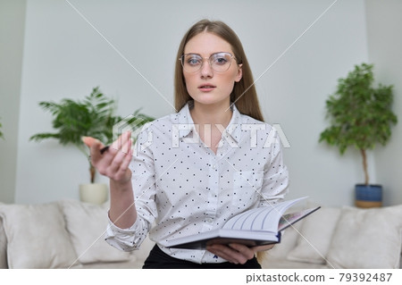 Young businesswoman with business notebook looking at webcam Young businesswoman with business notebook looking at webcam 79392487