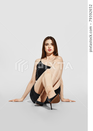 Trendy girl in tulle socks and eco leather short dress sitting on the floor Trendy girl in tulle socks and eco leather short dress sitting on the floor 79392652