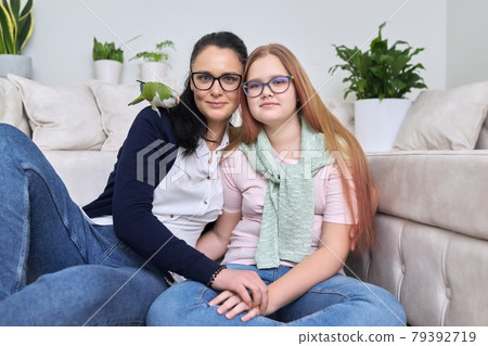 Friendly cheerful family, portrait of mom and teenage daughter, with green parrot 79392719