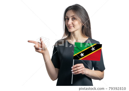 Happy young white woman holding flag St. Kitts and Nevis and points to the left isolated on a white background 79392810