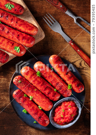 Sausages with ketchup, shot from the top on a dark rustic wooden table 79395485