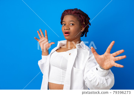 Young african american woman afraid and terrified standing against blue background 79396273