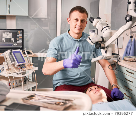 Dentist sitting beside female patient and giving thumbs up. Dentist sitting beside female patient and giving thumbs up. 79396277